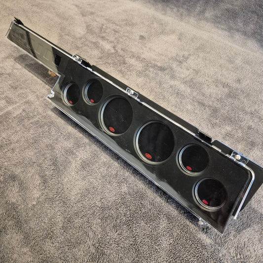 Black metal dash panel with SAAS gauges on a grey background