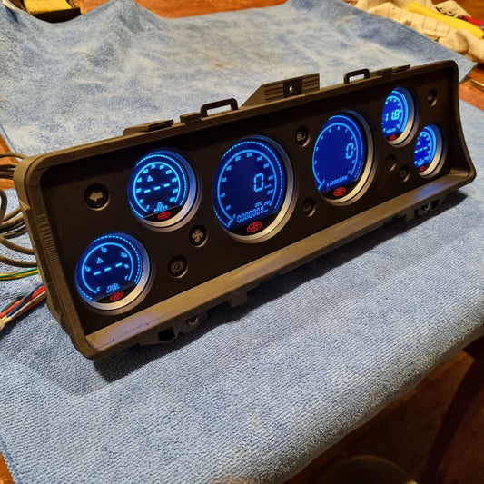 Control panel (Instrument Cluster Replacement) with illuminated gauges on a blue towel