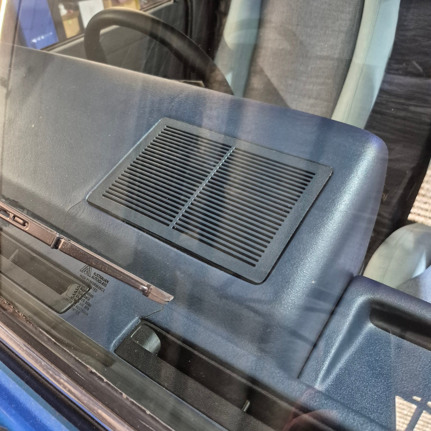 Car interior with a speaker grille and window control panel.