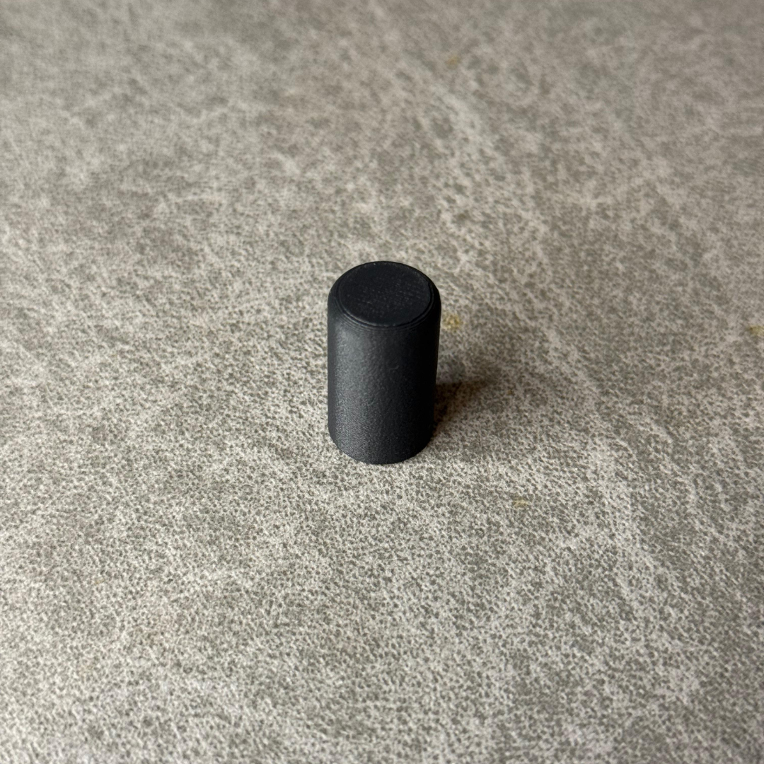 Black cylindrical object on a textured gray surface