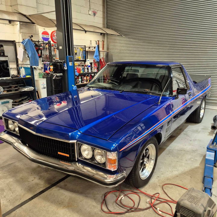 Blue HZ Holden Sandman ute with quad headlights, black grille with orange Sandman badge and side pinstripes