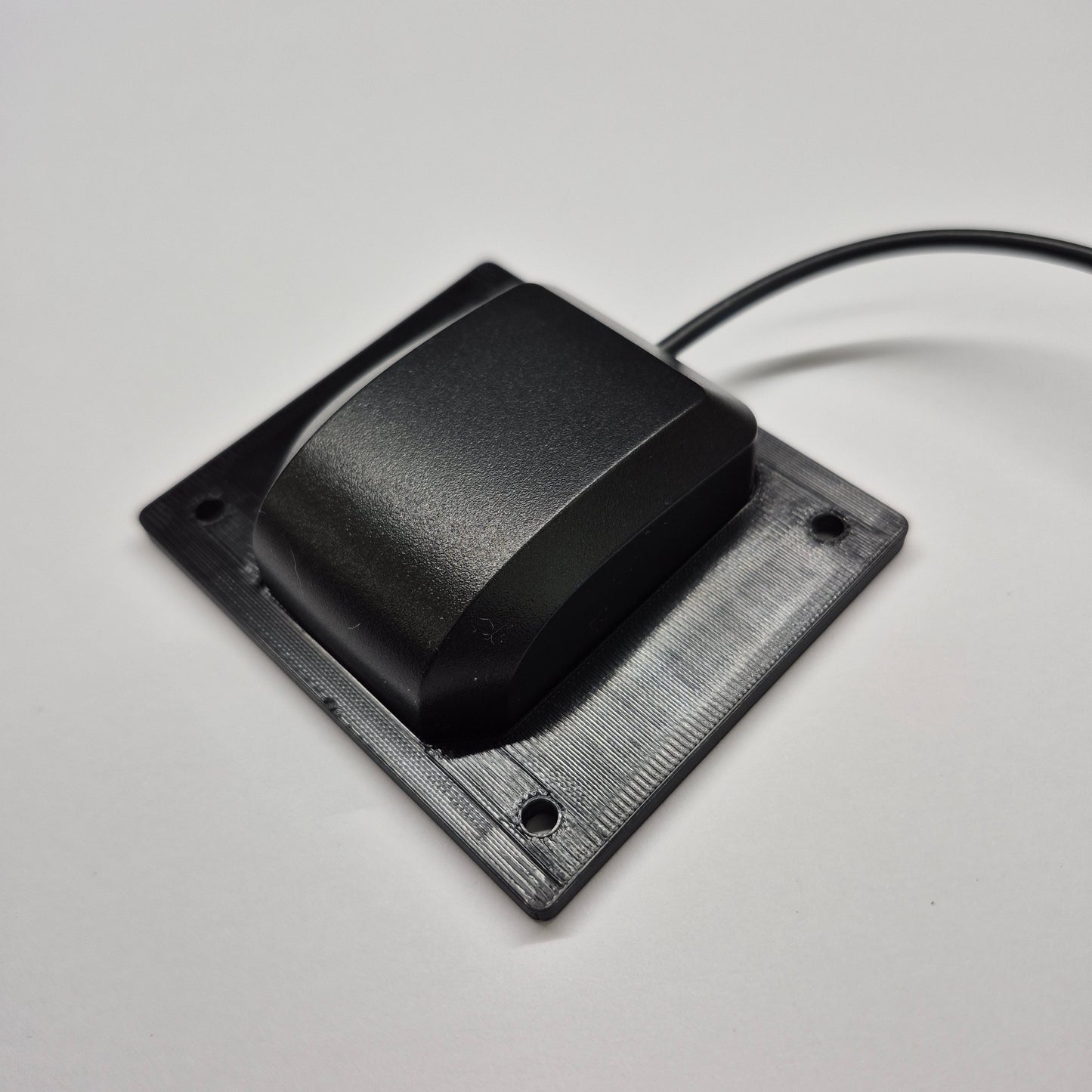 Black rectangular sensor with a cable on a light gray background