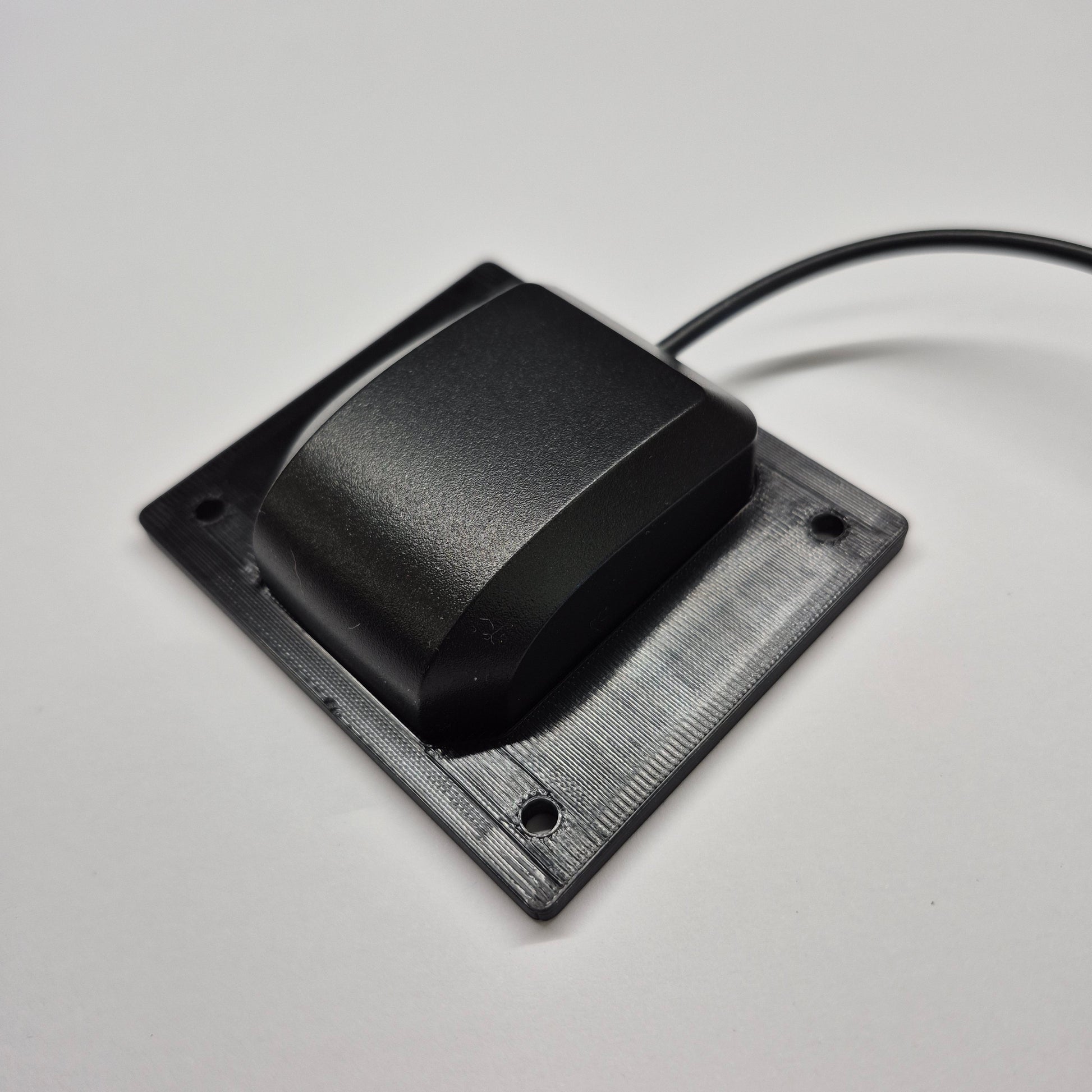 Black rectangular sensor with a cable on a light gray background