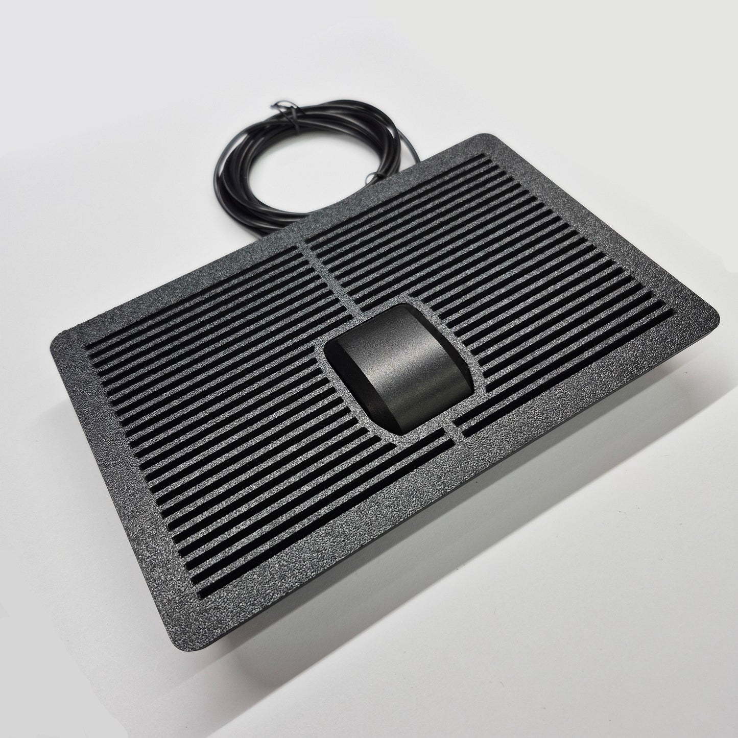 Black electronic device with cable on a light gray background