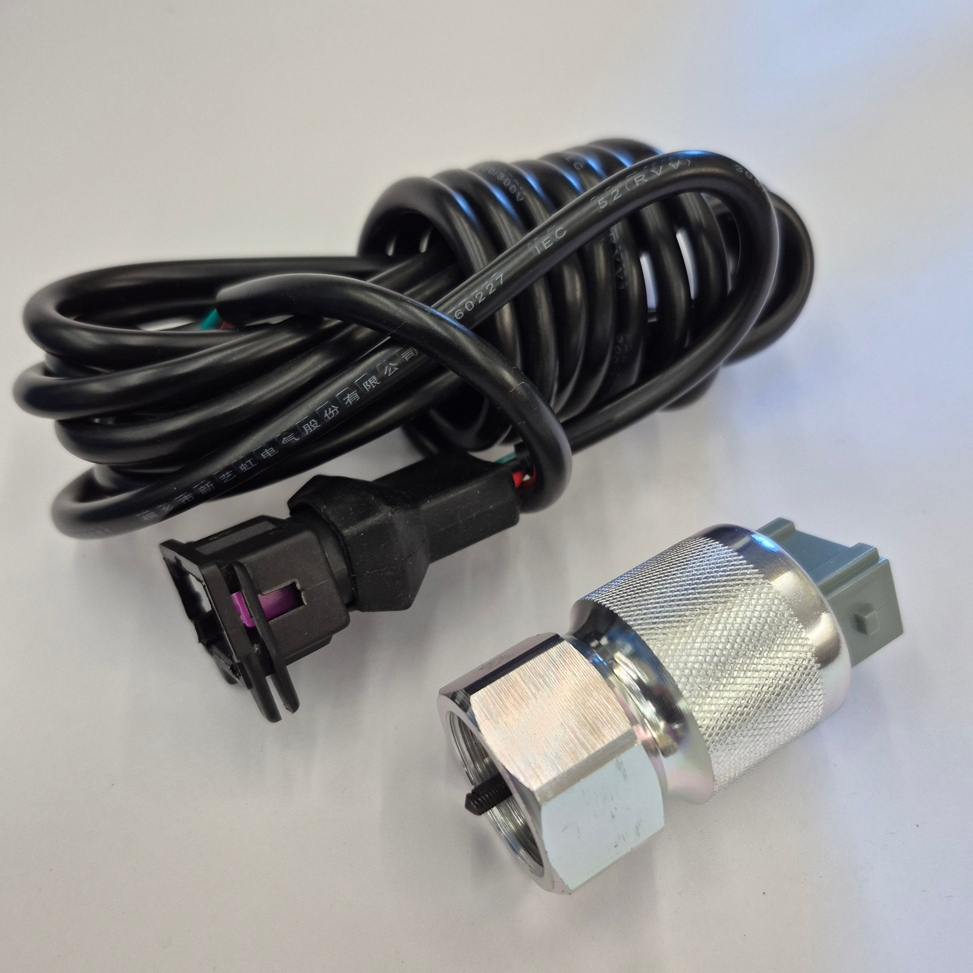 Coiled black power cable with plug on a white background