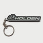A black and silver rubber keychain featuring the Holden lion logo and the word 'HOLDEN' in white, attached to a silver split ring on a light gray background.