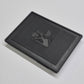 Black textured square mat with a logo on a light gray background