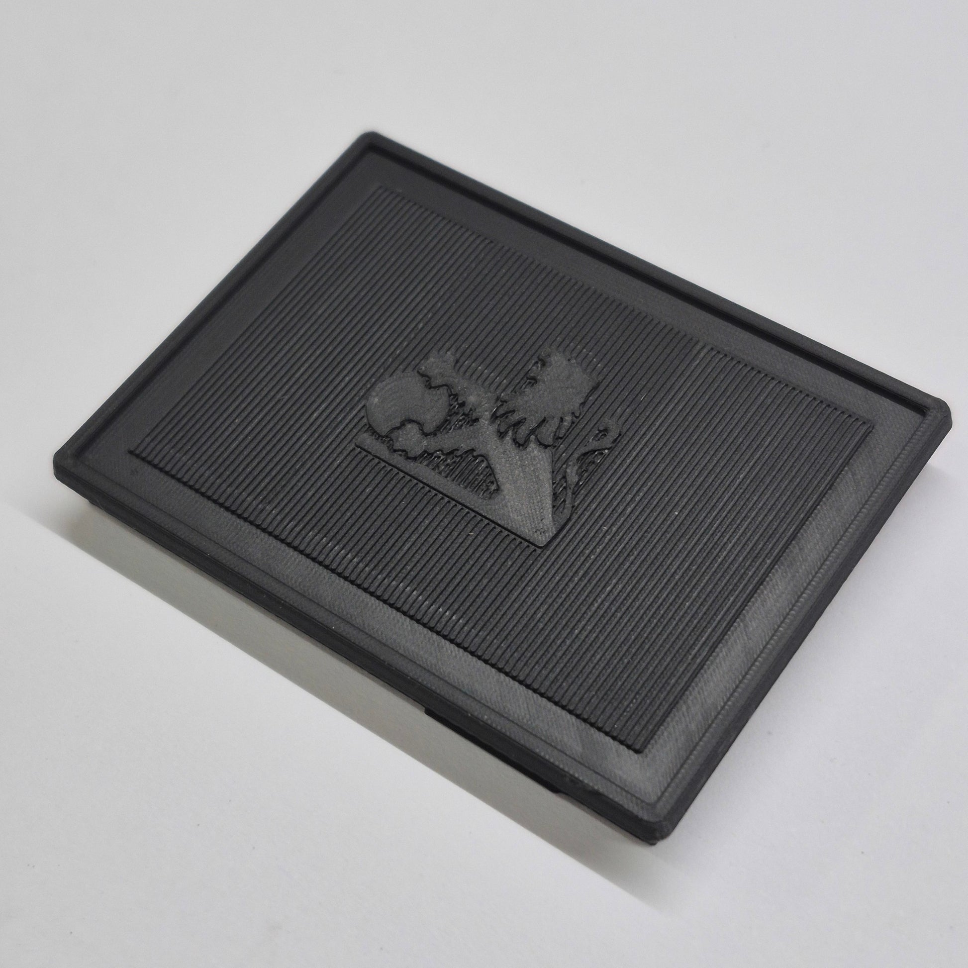 Black textured square mat with a logo on a light gray background