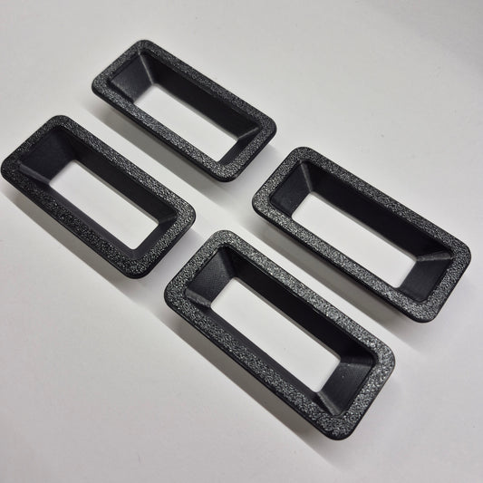 Four black rectangular baking pans with speckled texture on a light gray background