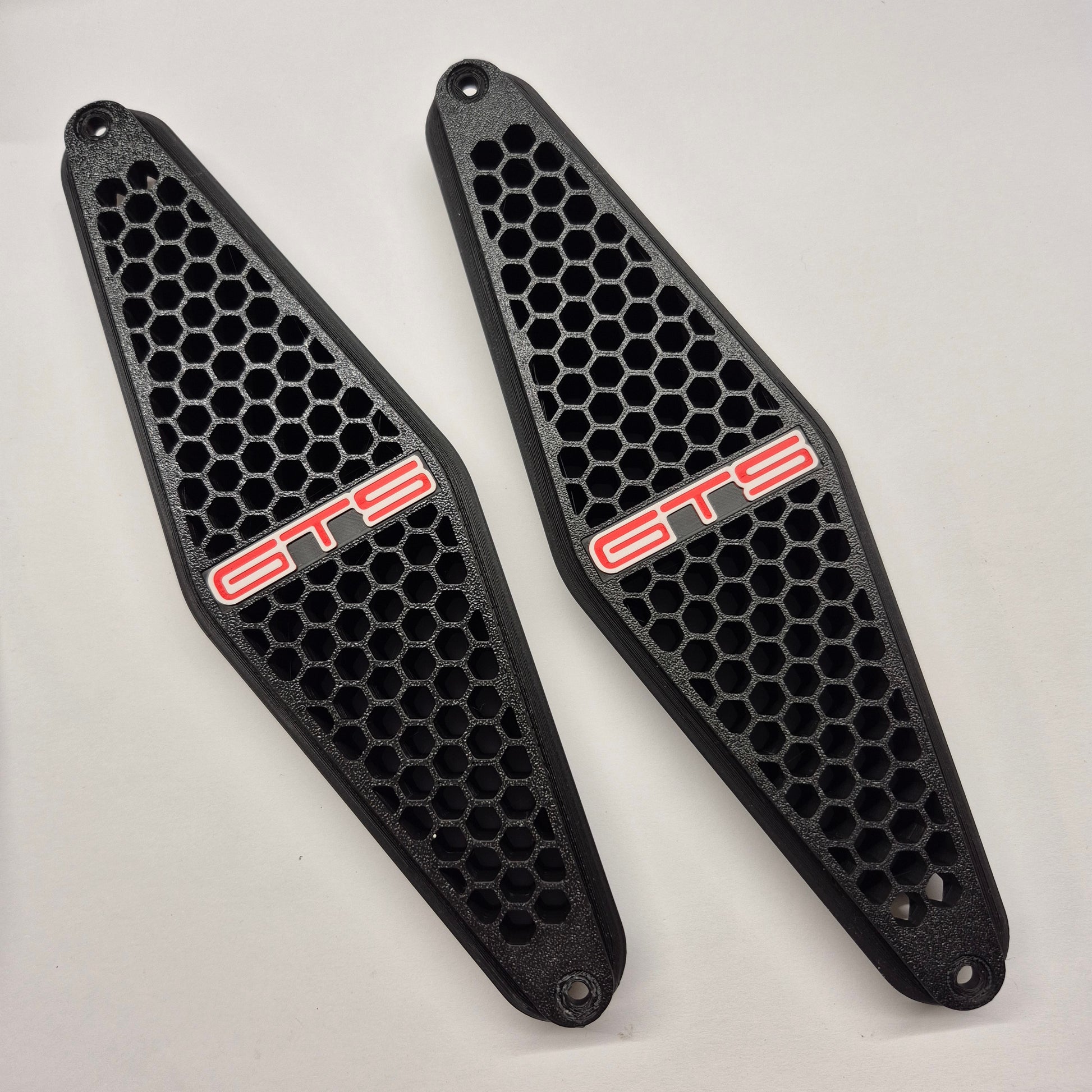 A pair of black honeycomb-patterned protective covers with red 'GTS' lettering, displayed on a light gray background.