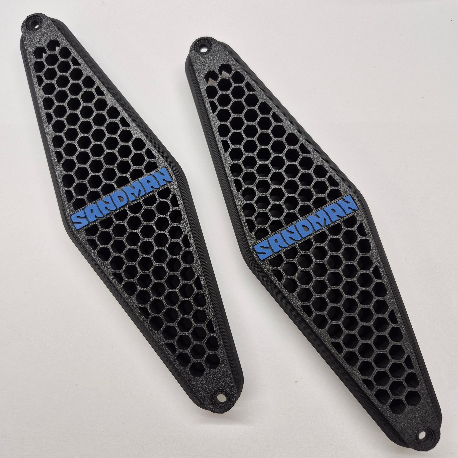 Two black honeycomb-patterned protective guards with blue 'SANDMAN' branding, displayed on a clean white background.