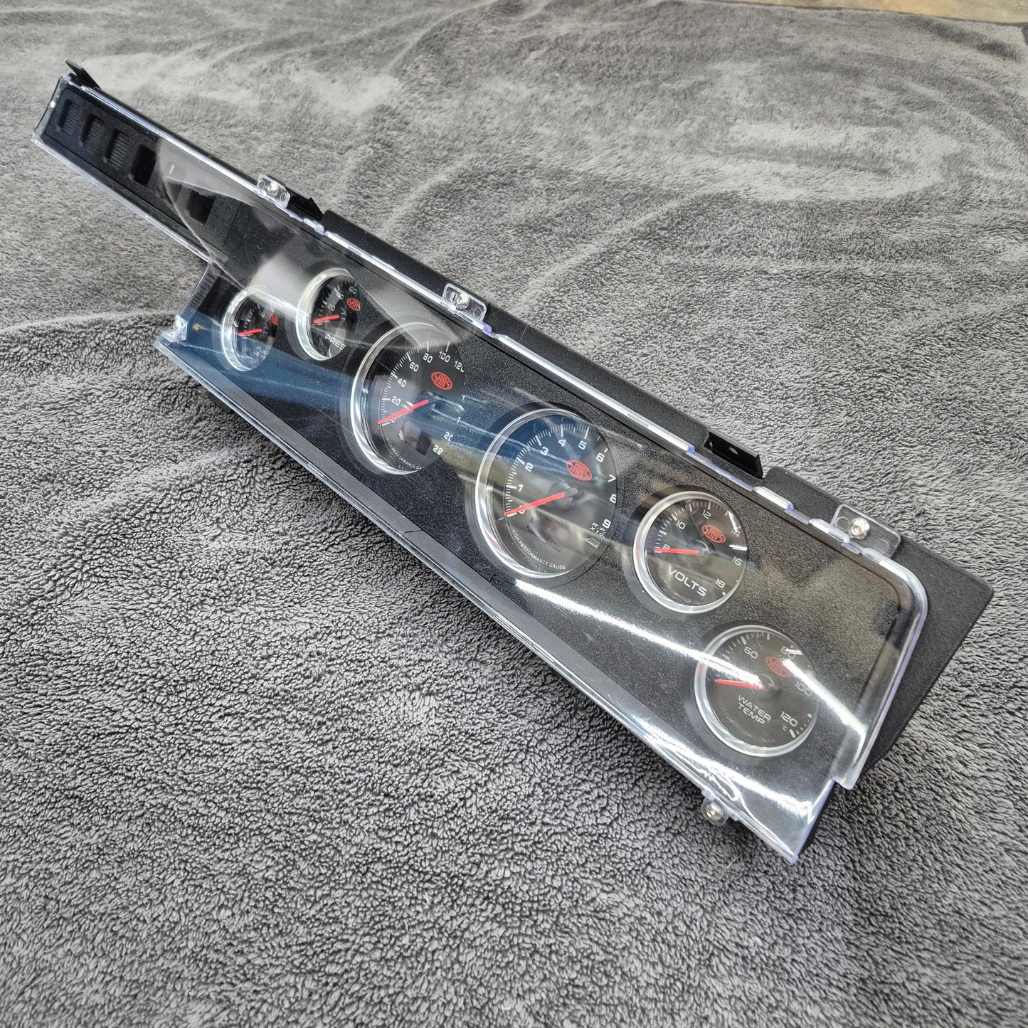 Set of car gauges in a plastic case on a textured gray surface