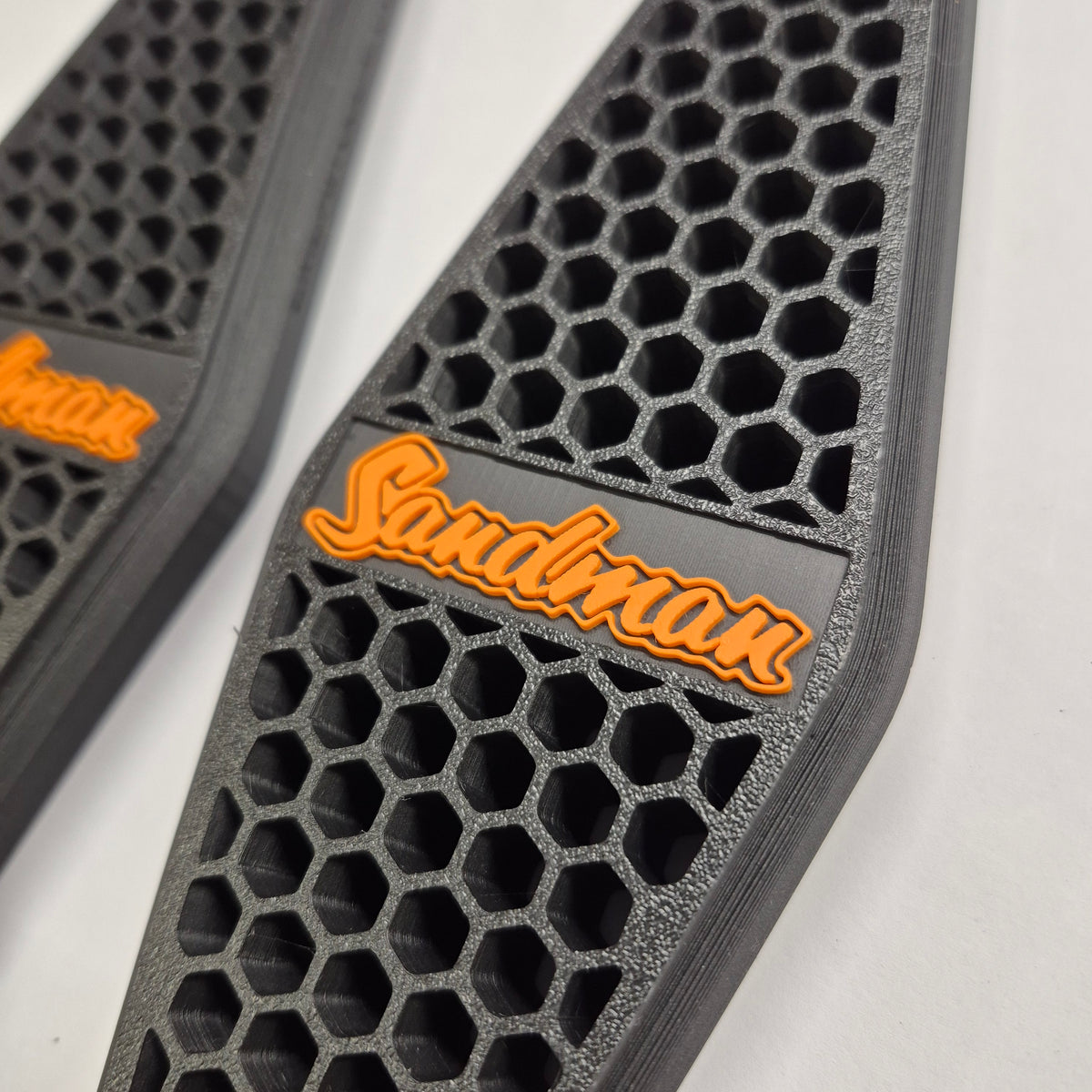Close-up of the raised orange Sandman script badge on the HQ–HJ Holden honeycomb side vent
