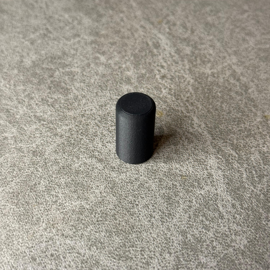 Black cylindrical object on a textured gray surface