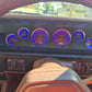 Car dashboard with illuminated gauges and a person's leg in the foreground
