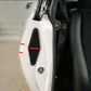 Close-up of a white vehicle door panel with a black mesh grille featuring the red SANDMAN logo, next to a black leather seat.